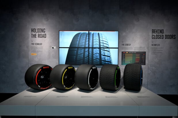 Pirelli Formula 1 tires, each with a different compound and color, are displayed under the titles 'Holding The Road' and 'Behind Closed Doors'. A large screen behind showcases the tire tread, emphasizing tire technology and strategy in Formula 1