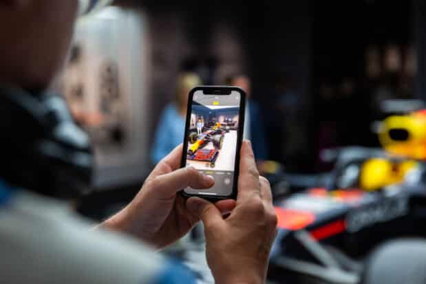A close-up of a visitor photographing a Formula 1 car at the F1 Amsterdam exhibition.