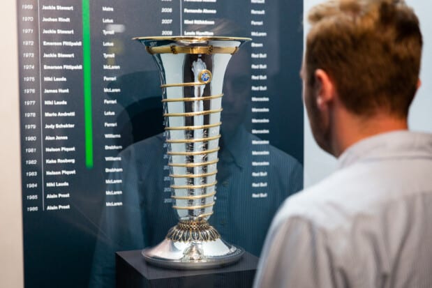 FIA Formula One World Drivers' Championship Trophy and back wall with trophy winners by year