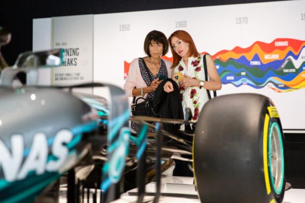 Visitors at the F1 exhibition observe a Formula 1 car