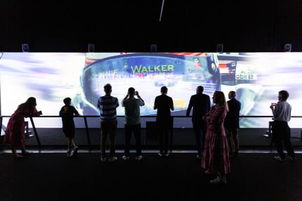 A group of people watch a projection at the Formula 1 exhibition.